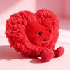 A bright red, fluffy heart-shaped plush cushion with embroidered features.