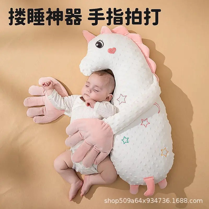 A baby is sleeping peacefully inside a white unicorn plush pillow with pink accents.