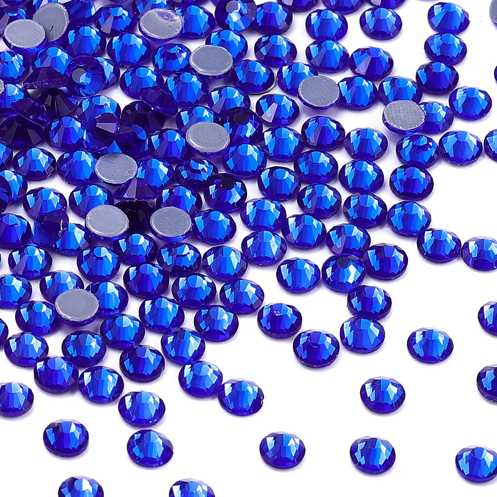 A close-up view of numerous round blue glass crystal rhinestones scattered on a white background.