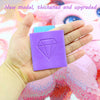 A hand holds a purple diamond-shaped clay piece used for diamond painting or crafting.
