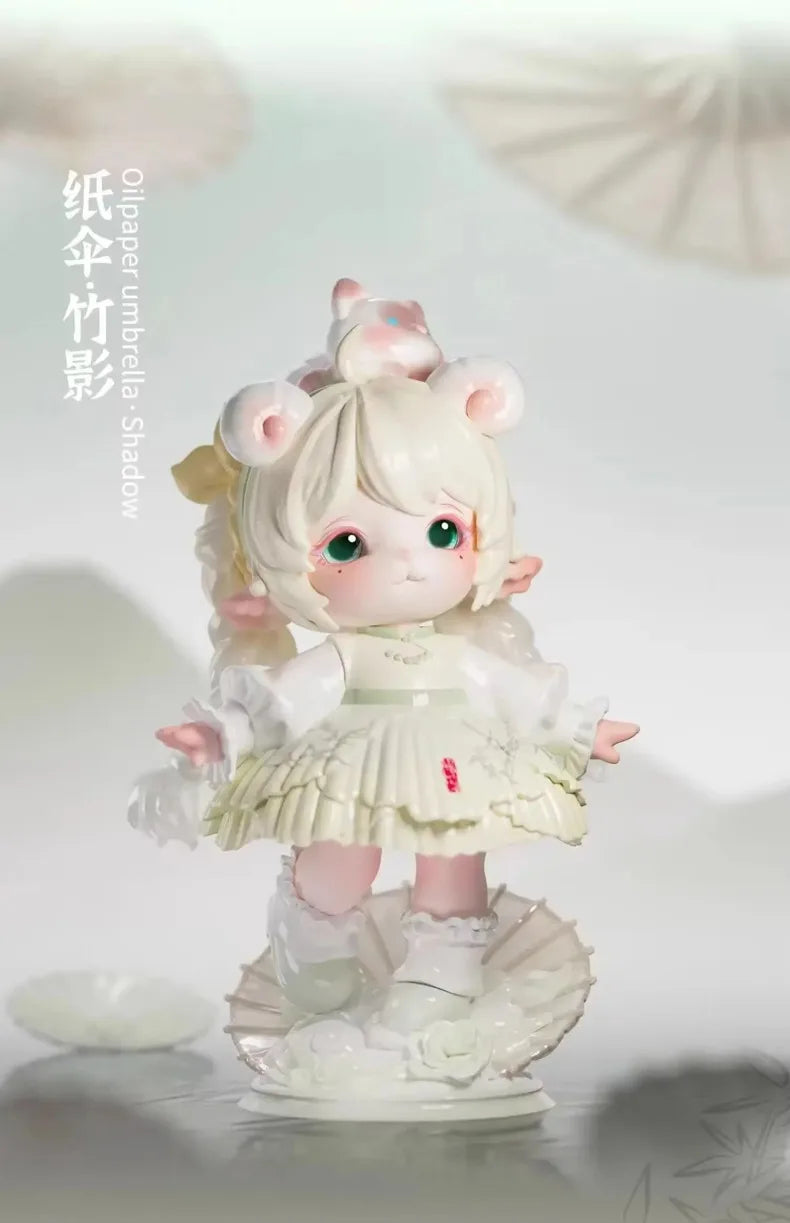 A white collectible figurine of a girl with pink ears and light blonde hair, dressed in a white dress, standing on a decorati