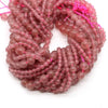 A tangled string of small, translucent pink and reddish-colored round beads for jewelry making.