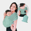 A woman is holding a baby in a teal X-shaped sling carrier with multifunctional back support.