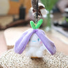 A small white bunny plush toy with purple fabric ears and a green leaf accent, hanging from a metal chain.