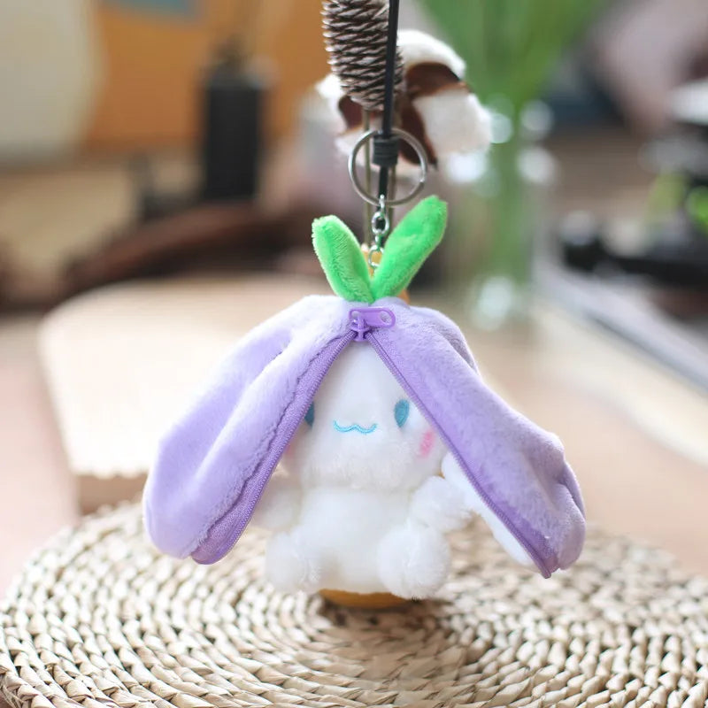 A small white bunny plush toy with purple fabric ears and a green leaf accent, hanging from a metal chain.