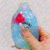 A hand holds a clear blue squishy milk bottle stress ball with a pink squishy inside.