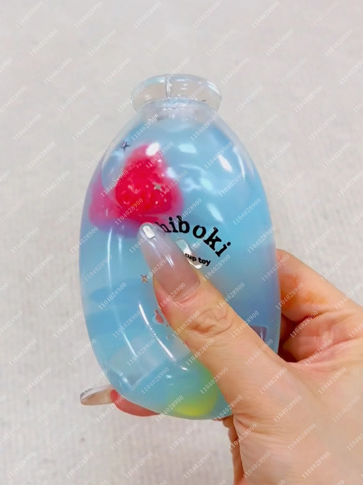A hand holds a clear blue squishy milk bottle stress ball with a pink squishy inside.