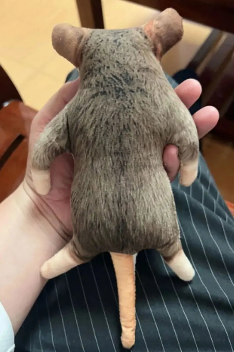 A brown, lifelike skeleton plush toy resembling a dog or cat is held in a person's hand.