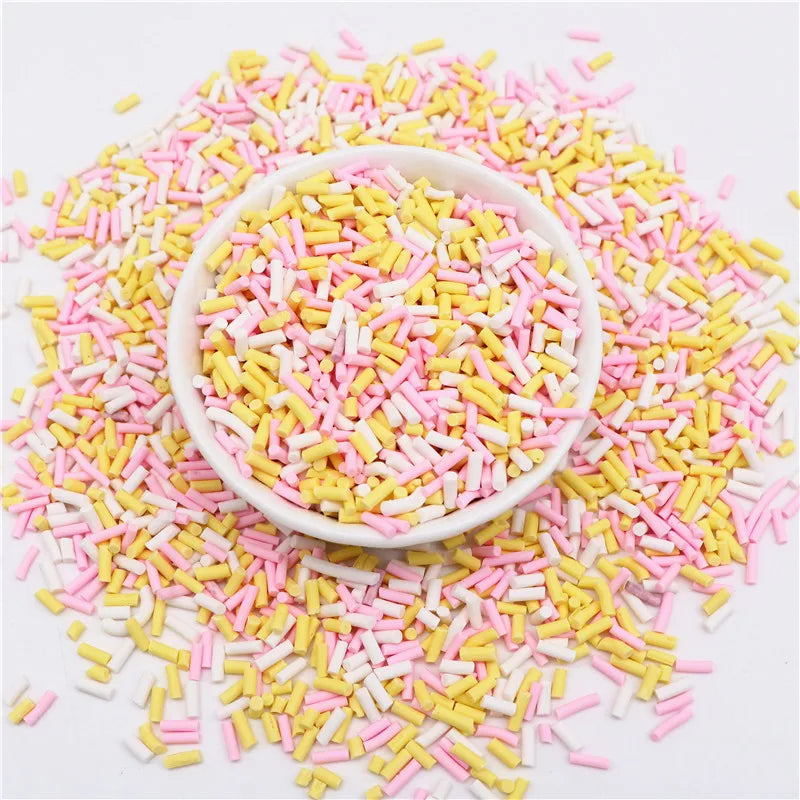 A bowl filled with colorful polymer clay slice sprinkles in pink and yellow scattered on a white surface.
