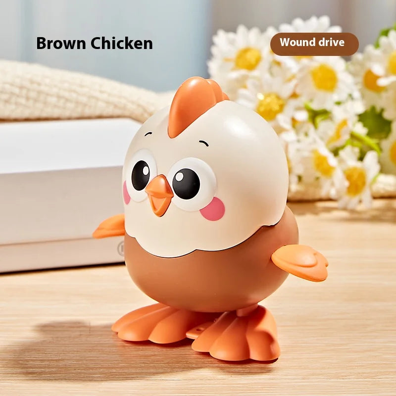 A brown chicken wind-up cartoon toy with a round body and orange beak sitting on a wooden surface.