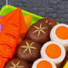 A single piece molding of a brown food item is shown in a green play kitchen set with various colorful food pieces.