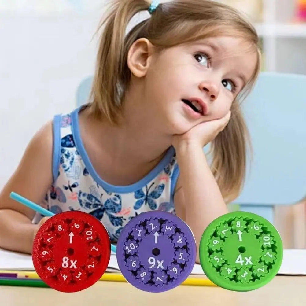 A young girl is holding four colorful math fidget spinners on a table.