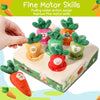 A hand is pulling a soft carrot toy with green leaves and a number from a wooden box for fine motor skill development.