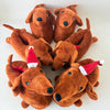 A group of brown dachshund plush slippers with red and white festive ear decorations.