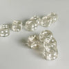 A collection of clear, transparent dice in various sizes scattered on a white surface.