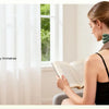A woman is using a green wireless neck and shoulder massager while relaxing indoors.