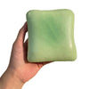 A hand holds a light green squishy toast stress relief toy.