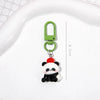 A small keychain featuring a cute panda character with black and white fur and a red nose, attached to a green split ring.
