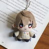 A small, fluffy plushie pendant charm of an anime character with red eyes, hanging against a page of text.