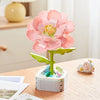 A pink rose flower building block bouquet set with green stems and white base on a wooden table.