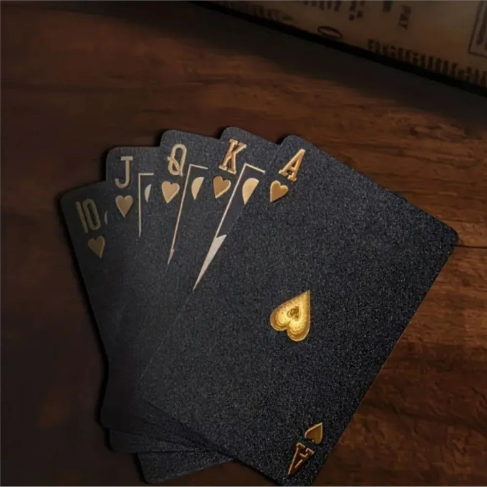 A stack of dark gray frosted poker playing cards showing the Ace through Ten, resting on a wooden surface.