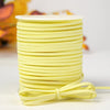 A stack of bright yellow velvet faux suede braided ribbon rolls for crafting and gift wrapping.