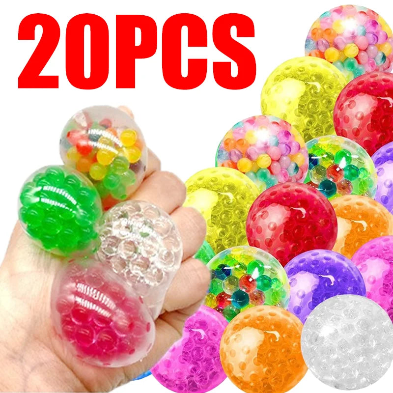A hand holds a variety of colorful, translucent rubber stress balls in various shades including green, pink, yellow, and purp