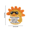 Handmade crochet sunshine doll with an orange textured face and a white tag featuring an inspirational message