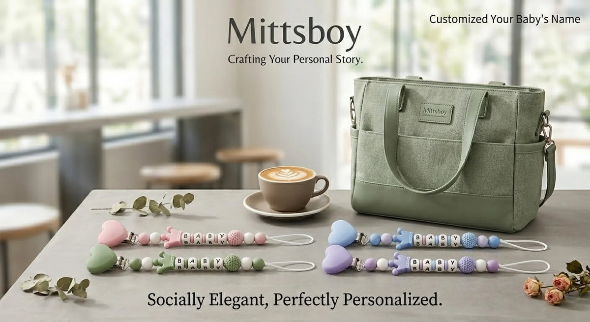 A green silicone pacifier clip with a name charm rests on a wooden table next to various floral leaves.