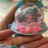 A hand holds a Teenieping Shining Meteor Aurora doll featuring a translucent body, pink bow, and gold crown.