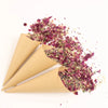 Dried rose petal confetti scattered from a rolled paper cone