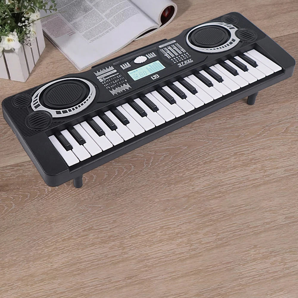 A black 37-key electronic keyboard with a microphone rests on a wooden surface.