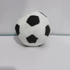 A white and black handmade crochet hacky sack ball is shown on a white surface.
