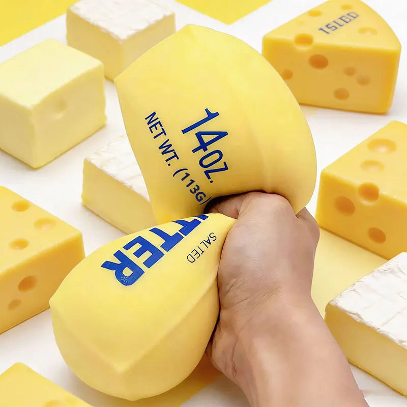 A hand squeezes a yellow butter stick squishy fidget toy with salt lettering on it.