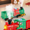 A red and green electric universal train toy is shown on a wooden floor next to a Christmas tree.