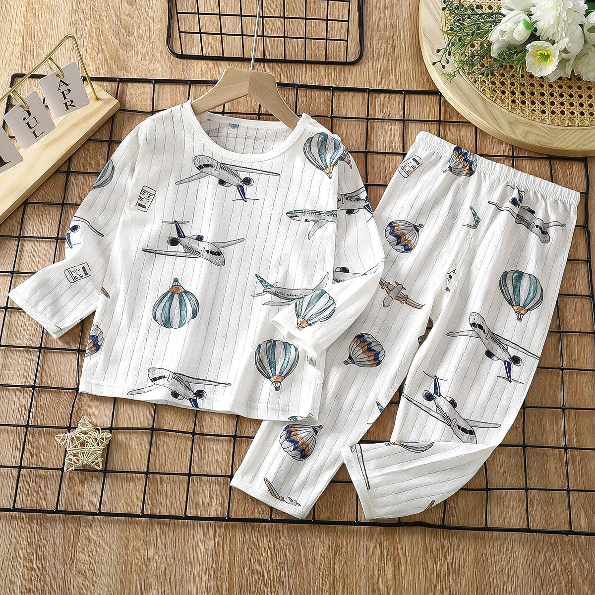 White long sleeve cotton pajama set for kids featuring a pattern of airplanes and hot air balloons.