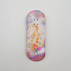 A wooden fingerboard deck with a UV-printed graphic of a white unicorn and colorful flowers on a purple background.
