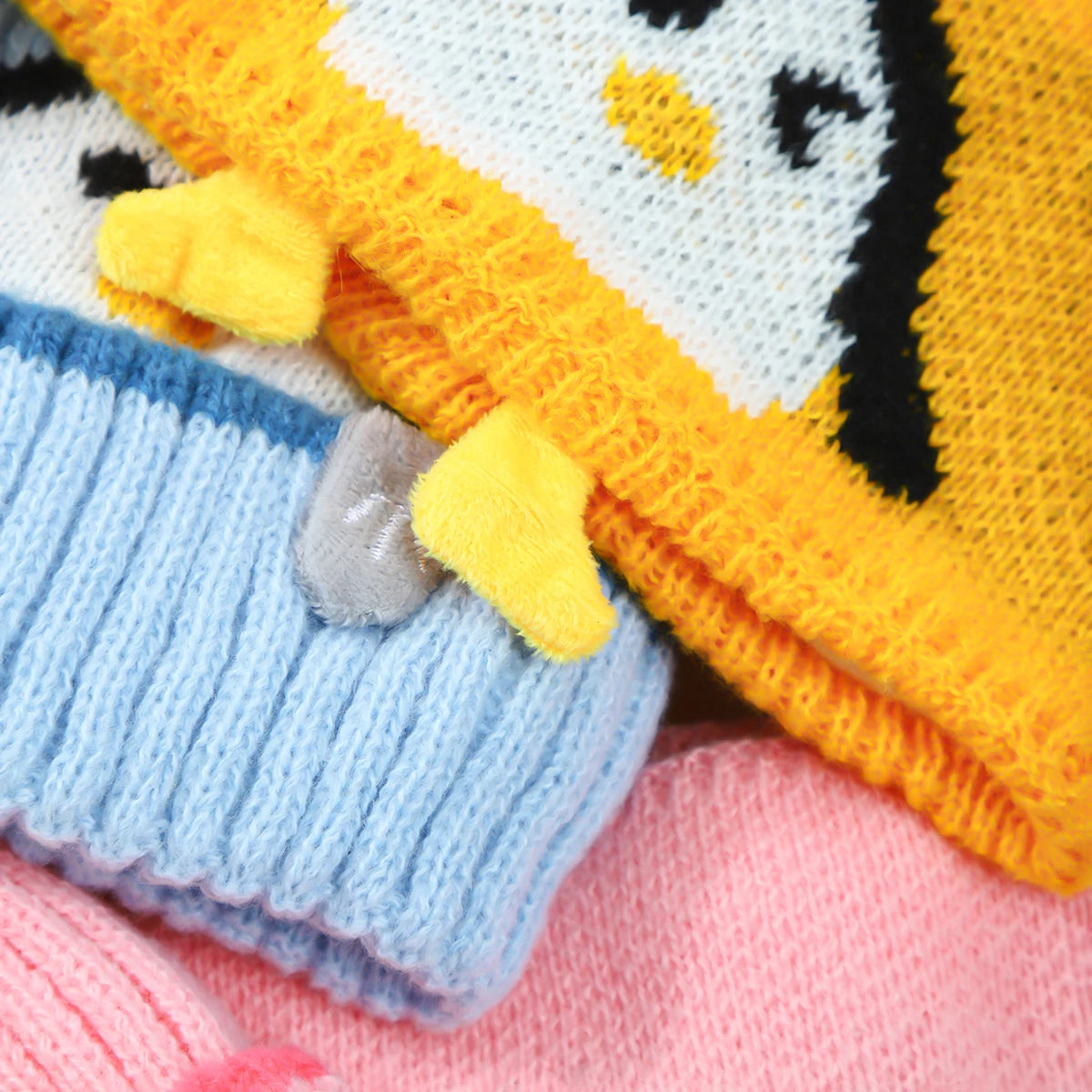 A set of adorable penguin knit items including a yellow and white striped hat or scarf and a blue knitted item.
