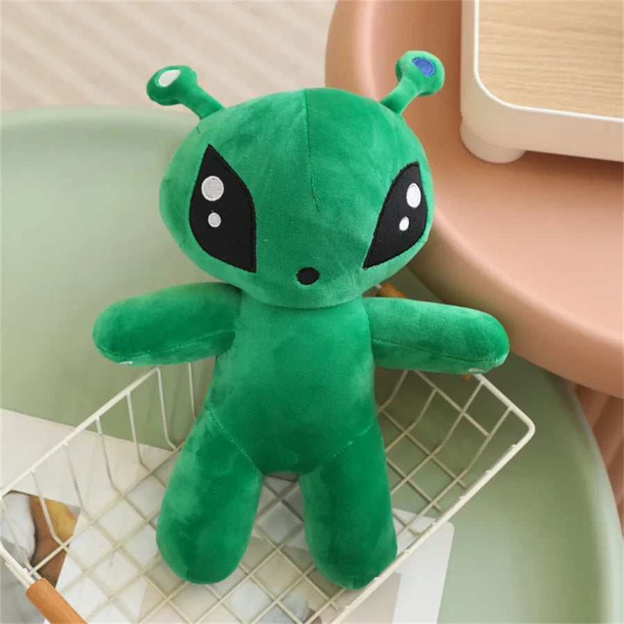 Adorable green alien plush toy with large eyes and long ears sitting in a white wire basket.