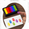 A hand holds a black ink pad with six rectangular gradient colored pads, showing various rainbow colors for crafting.