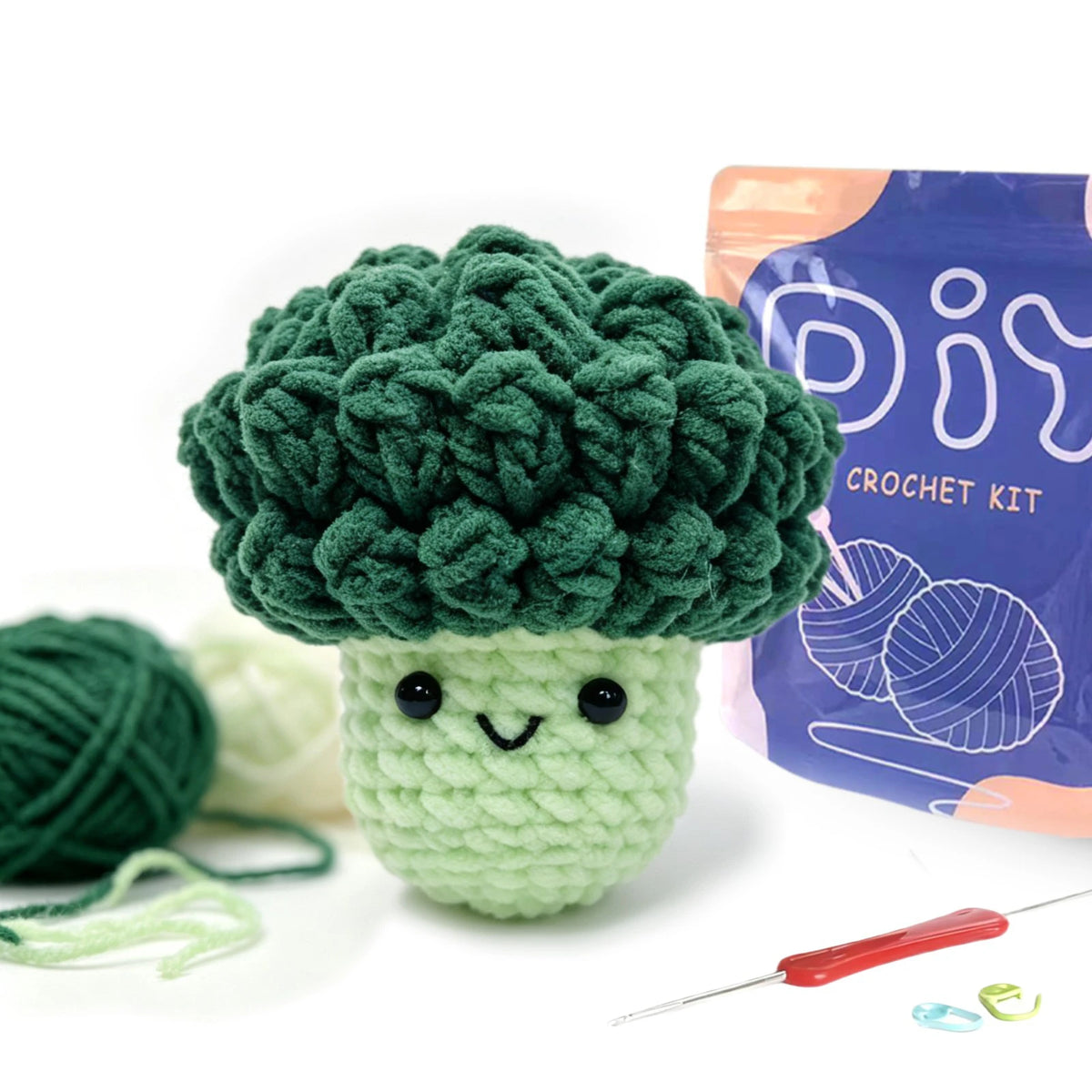 A crocheted broccoli head shaped like an avocado, next to yarn and a crochet needle.