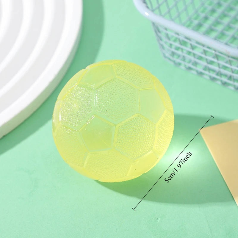 A round, translucent yellow football-shaped squishy fidget toy resting on a green surface.