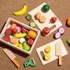 A wooden magnetic fruit cutting play set featuring various fruits like mango, orange, and apple on a light wooden board.