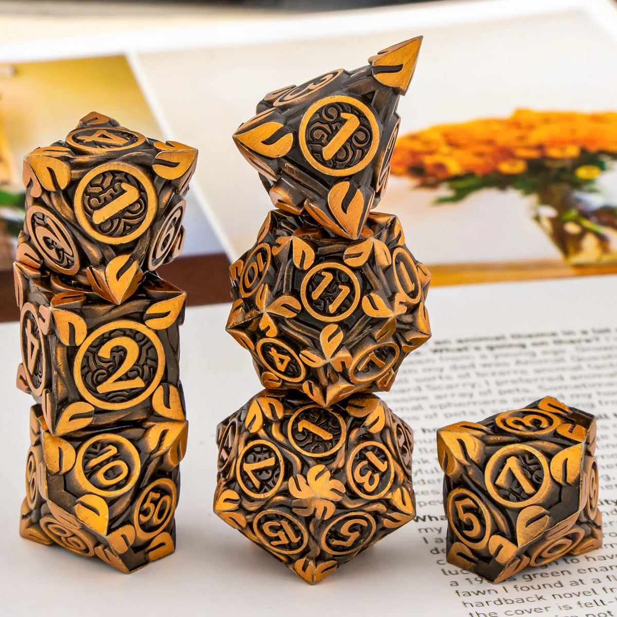 A stack of seven metal dice in gold and black designs for tabletop role-playing games