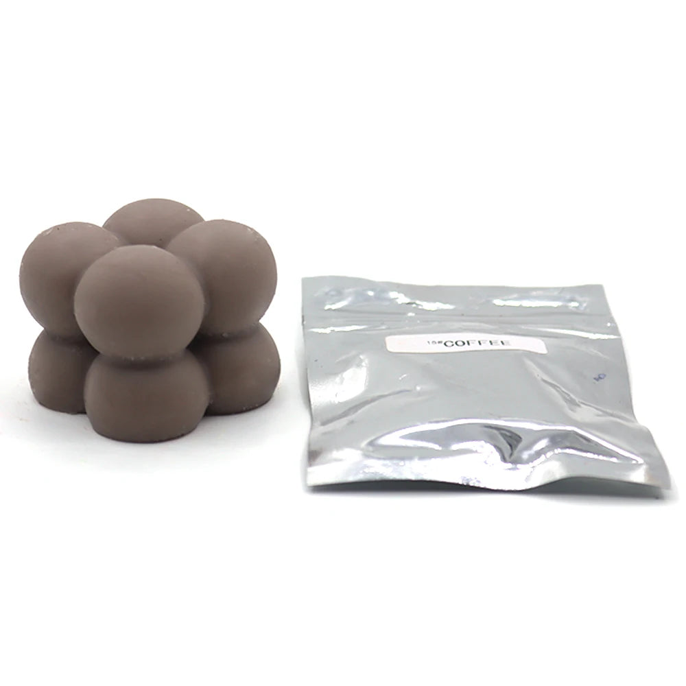 A pile of round, gray candle dye chips next to a sealed plastic bag labeled coffee.