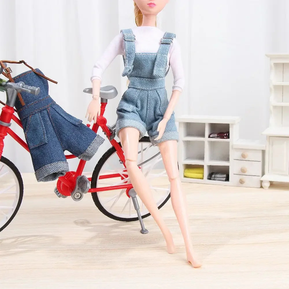 A mini doll wearing a denim overalls set and white t-shirt standing next to a red bicycle.
