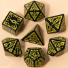 A set of seven fantasy carved polyhedral dice in black and yellow on a beige surface.
