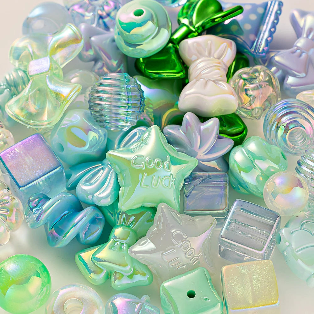 A close-up of iridescent and pastel green acrylic bow and flower beads for DIY jewelry making
