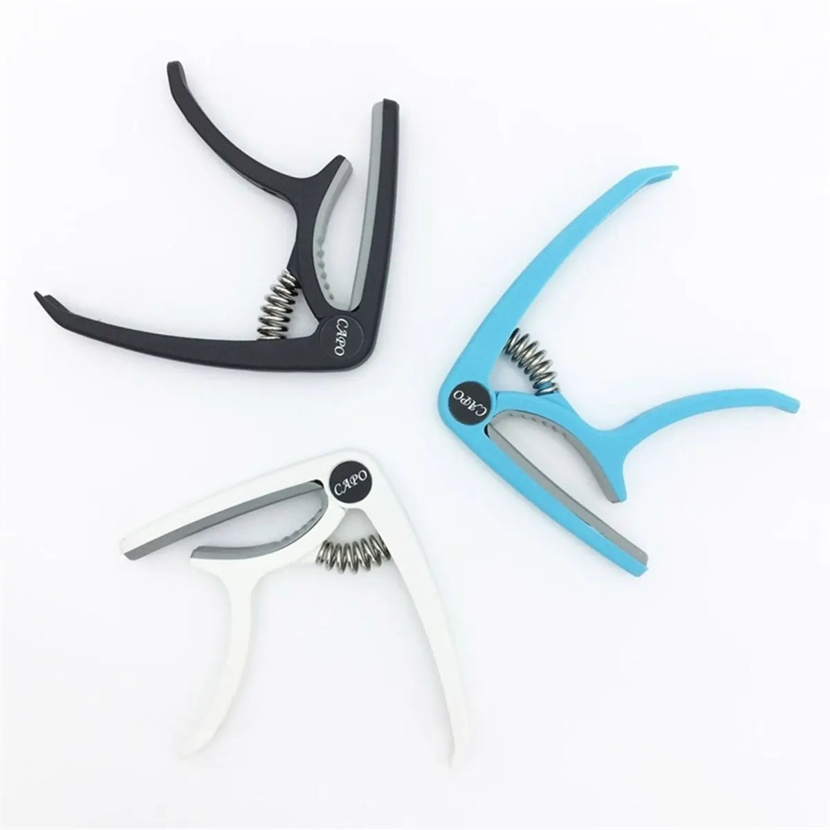 Three versions of a universal guitar capo are shown in black, blue, and white.