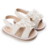 Pair of light beige baby first walker sandals with floral cutouts and soft anti-slip soles
